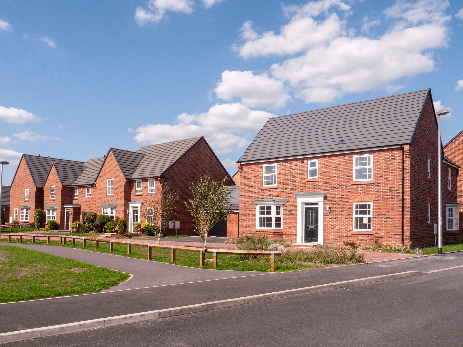 A row of new build, detached, brick houses, with a green and walkway in front; our Conveyancing Solicitors in Lytham discuss new build property ownership and how we can help.