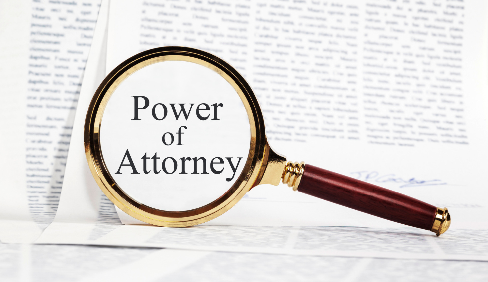A magnifying glass showing 'Power of Attorney' over a pile of papers.