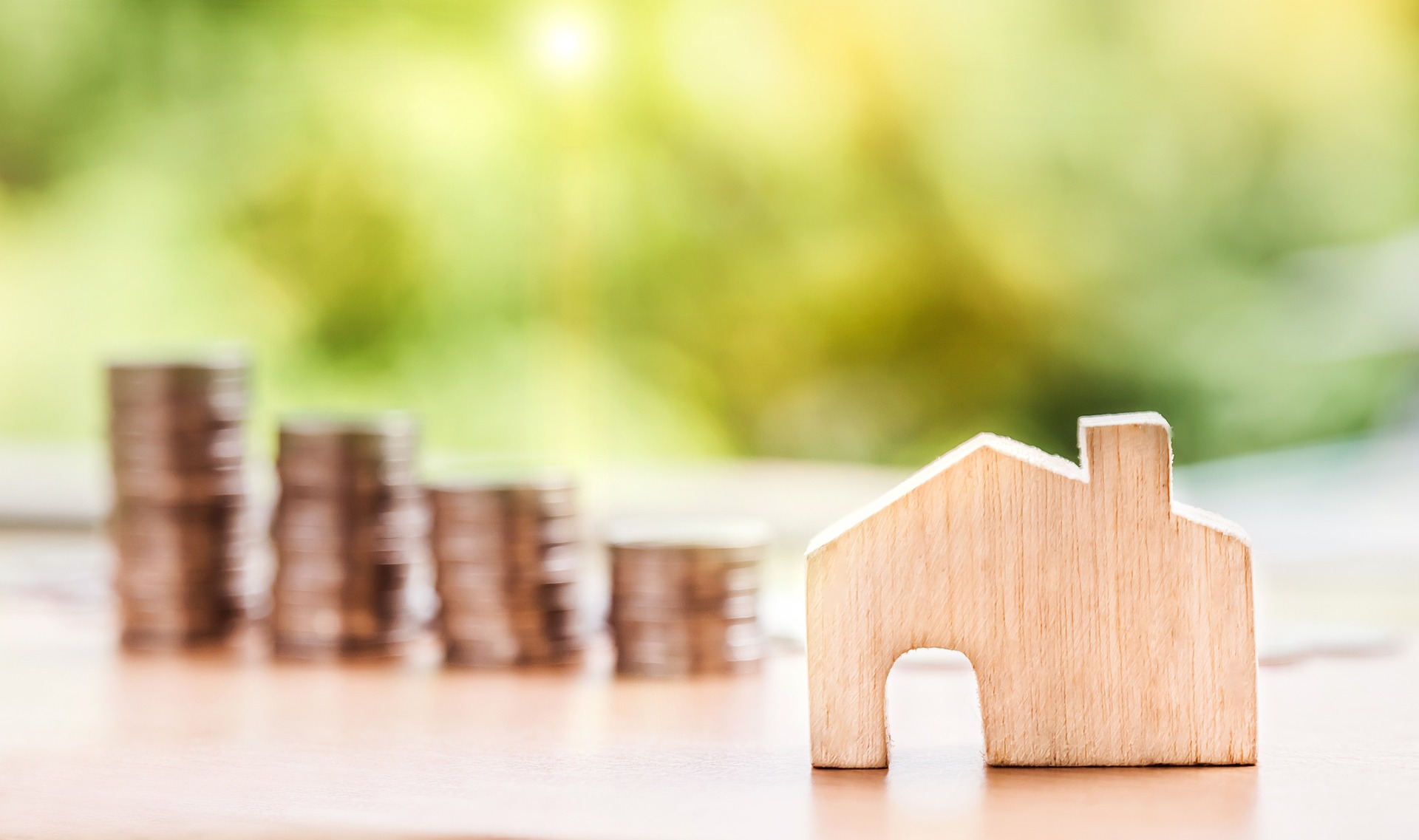 A wooden house, with money stacked in the background; our Conveyancing Solicitors in Lytham discuss Lifetime ISA closures, and how they could impact your property purchase.