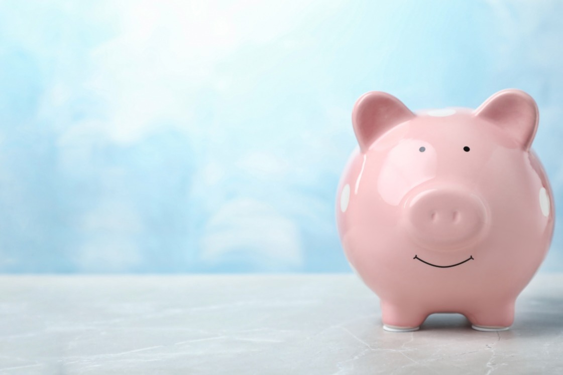 A pink, ceramic piggy bank, with a smiley face, against a blue background; our Wills Solicitors can assist with the preparation of your Will and estate planning to protect your future.  Click this image to visit our fees page, and find out how much our Wills Solicitors charge.