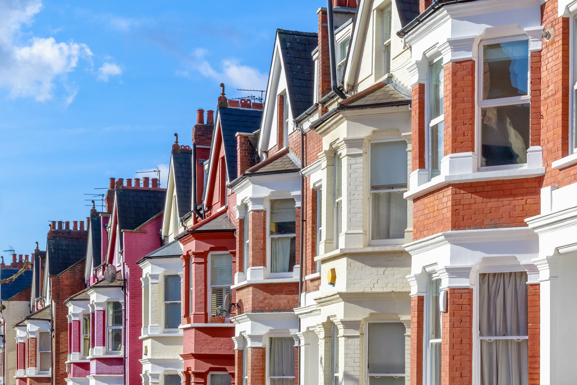 A row of terraced houses, in various bright colours; our conveyancing solicitors discuss whether it is better to use a Conveyancing Solicitor.