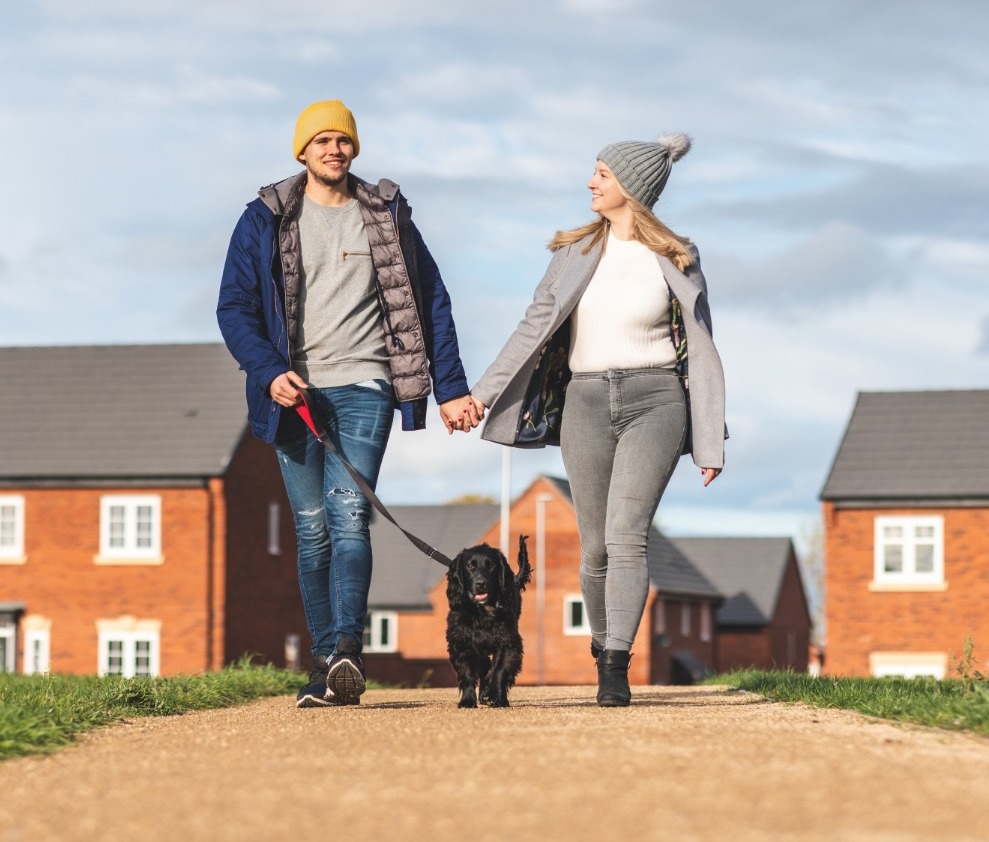 A couple walking their dog through a housing estate, with a link to our Conveyancing Solicitors' page explaining jointly owned property.