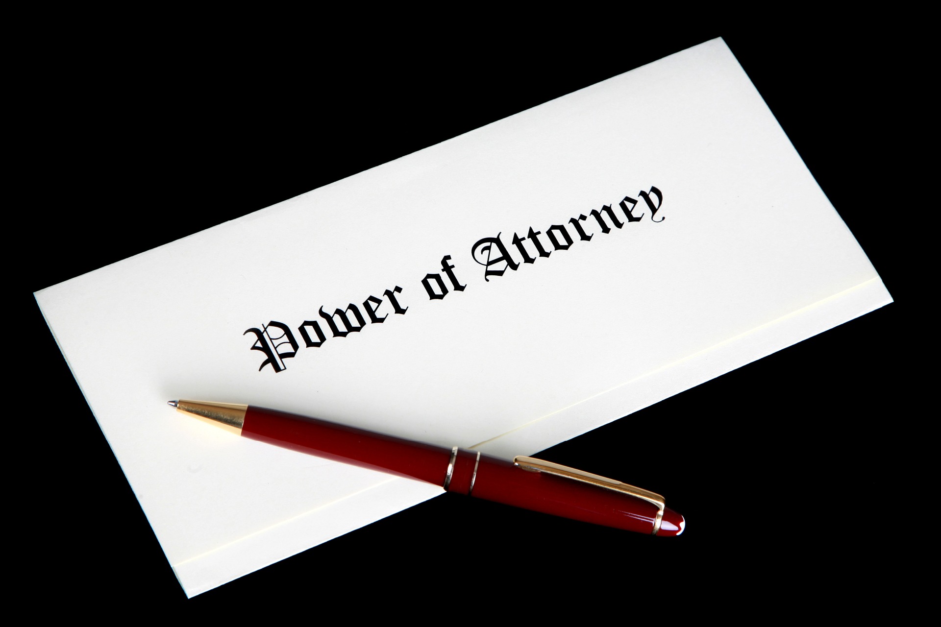 A piece of paper folded into three, with Power of Attorney written on, with a red pen resting on the document.