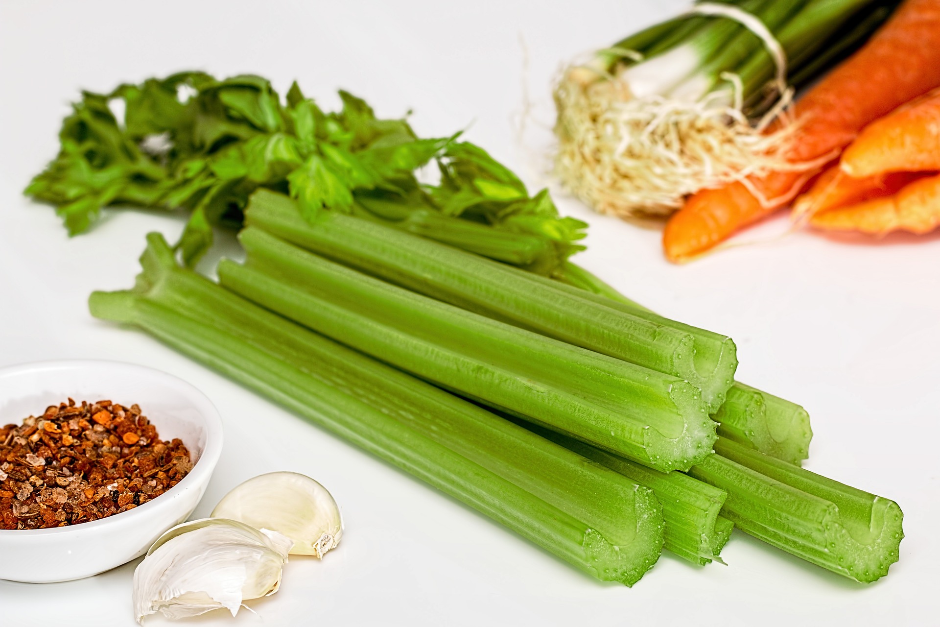 A stack of celery, with other vegetables in the background; our celery allergy compensation solicitors can assist you with making a compensation claim.  Click this picture to read more about celery allergy compensation claims.