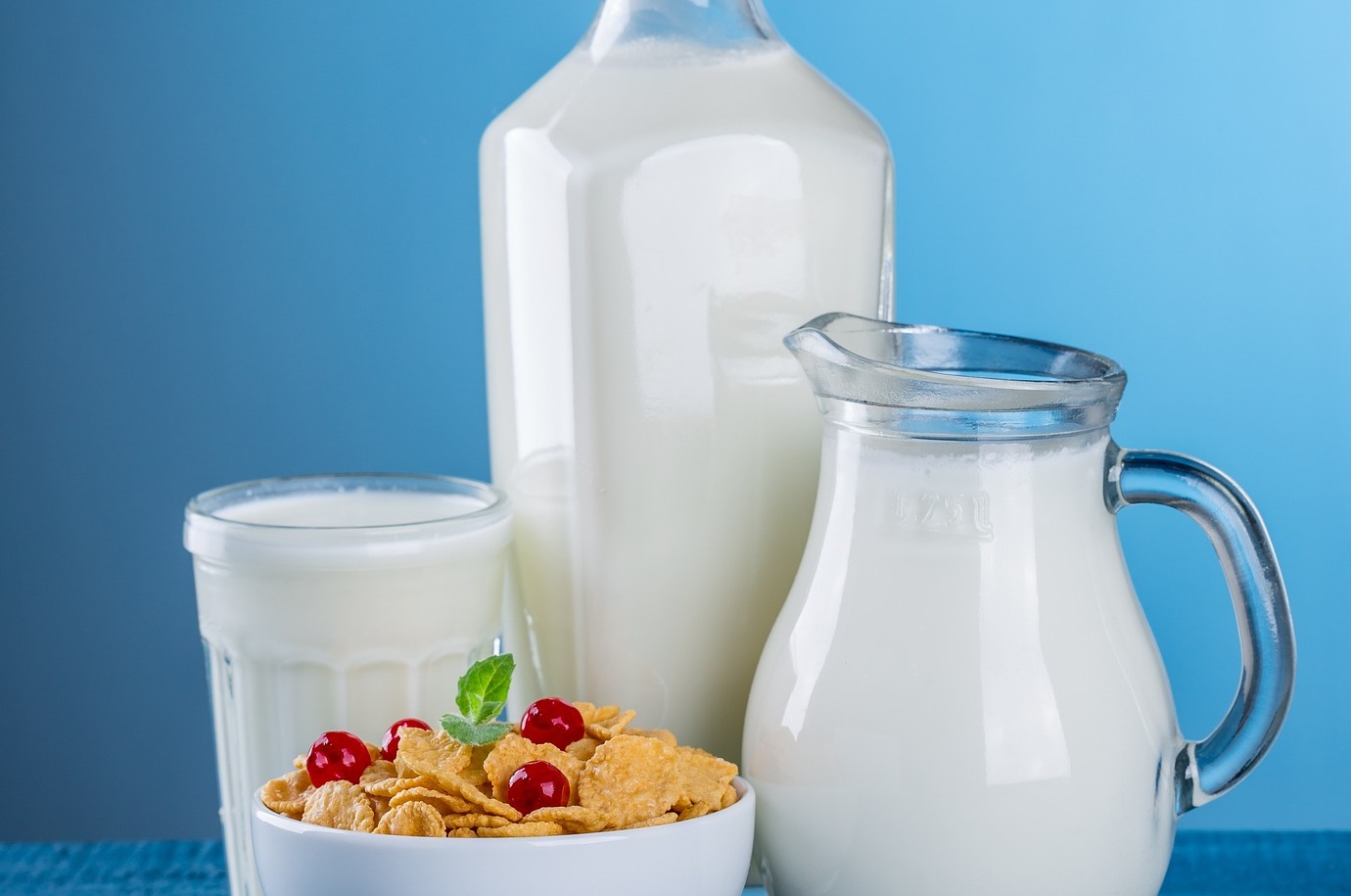 Various jugs and cups of milk, with a bowl of cereal; our milk allergy compensation solicitors can assist you with making a compensation claim.  Click this picture to read more about milk allergy compensation claims.