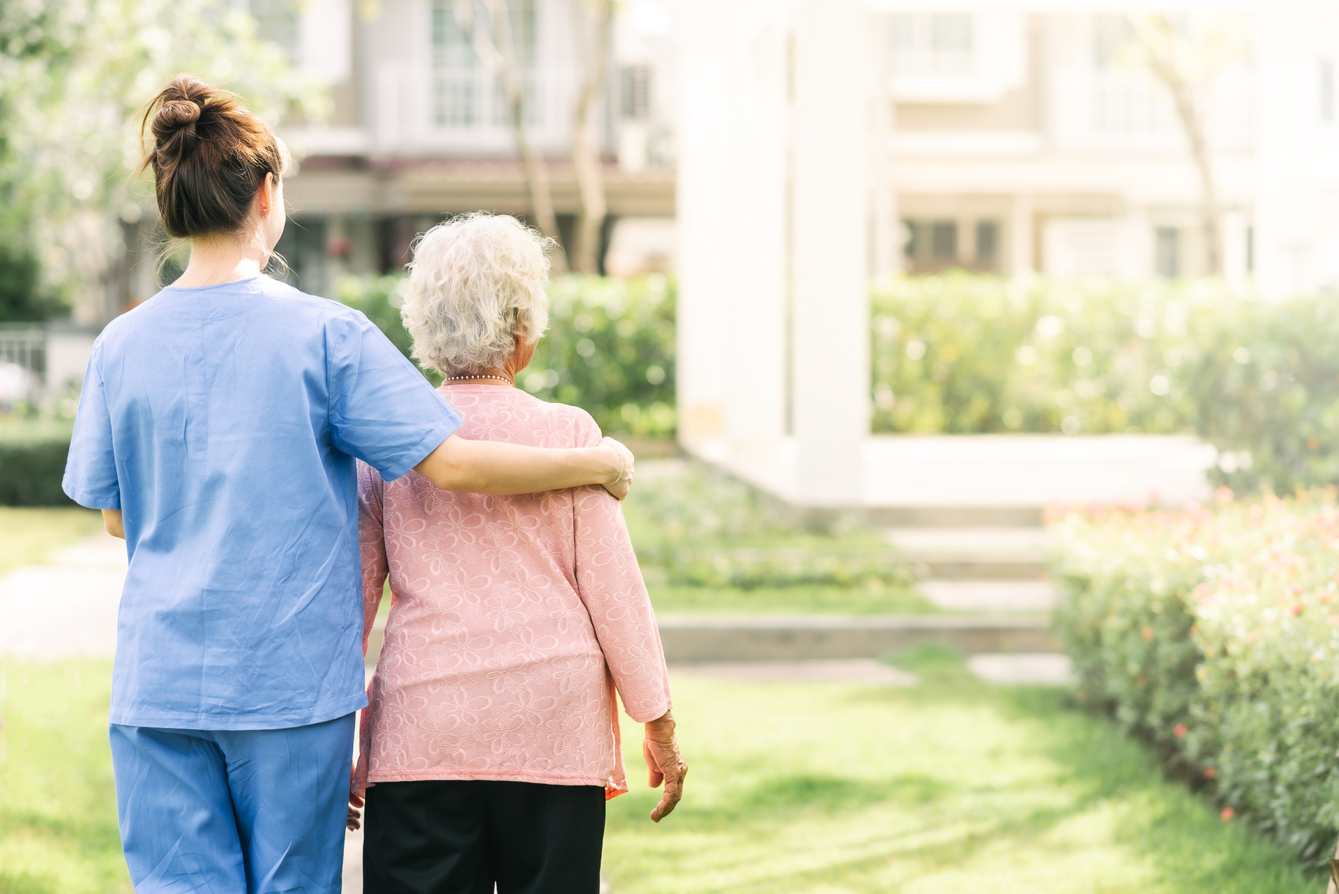 An older person, being supported by a professional, in the grounds of a care home; our care home negligence solicitors discuss how to make a claim for compensation if your loved one has been the victim of negligence in a care home.