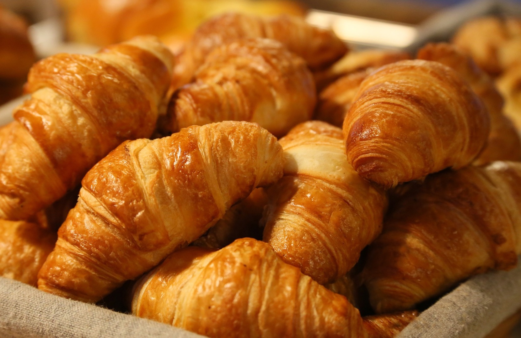 A basket of freshly baked croissants.  Click the picture, or the link below, to go to our personal injury solicitors’ no win no fee coeliac negligence compensation claims page.