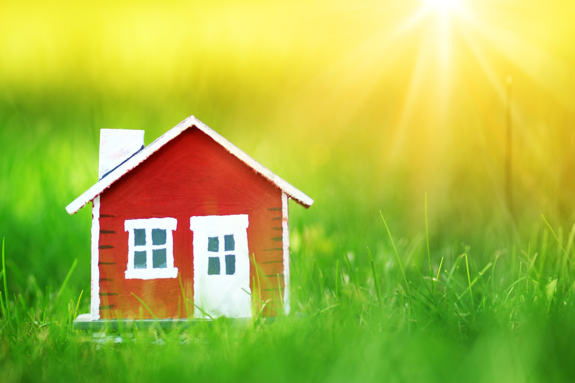 A green field, with a wooden, red house with white door and window; our Conveyancing Solicitors in Preston discuss how many people move house, and how our Conveyancing Solicitors can assist.
