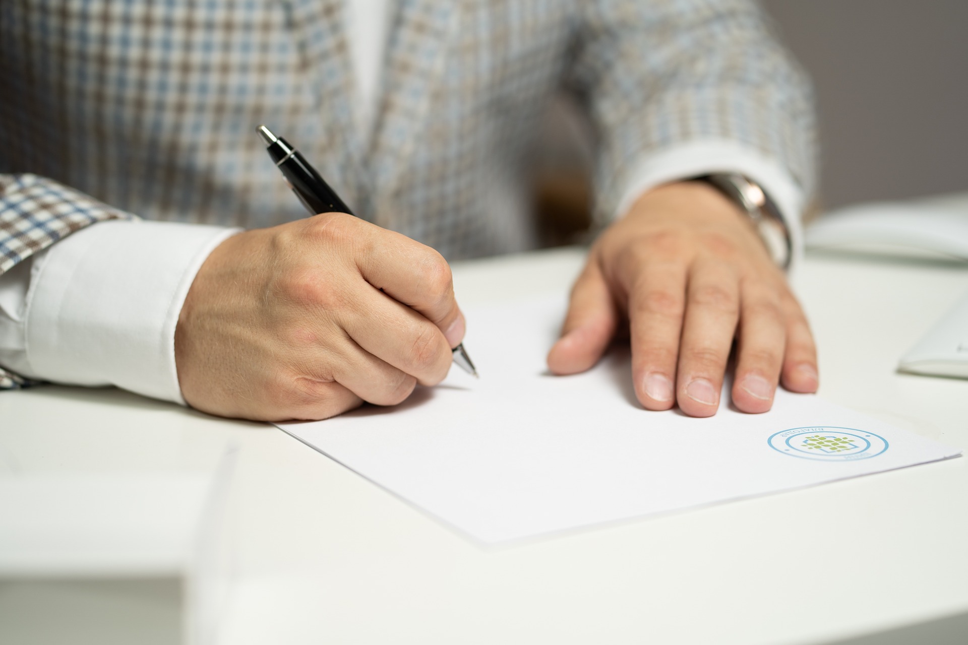 A person dressed smartly, signing a legal document; click this image to visit our Wills Solicitors' page on how to sign a Will.
