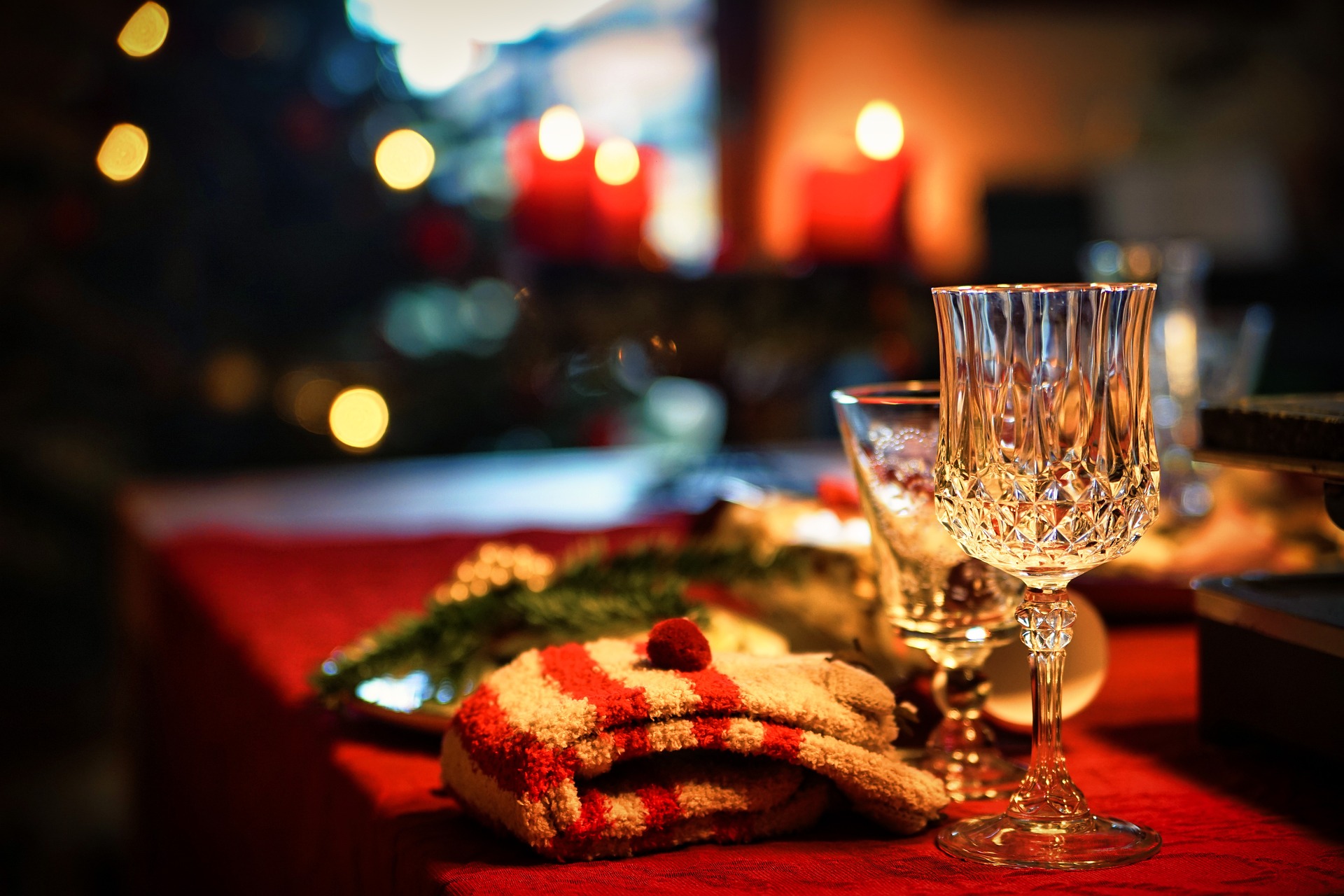 A table set for Christmas, with plates, wine glasses, a Christmas tree and candles in the background, with Christmas-themed socks and other presents around; our No Win No Fee Solicitors discuss food allergies at Christmas and how to stay safe.