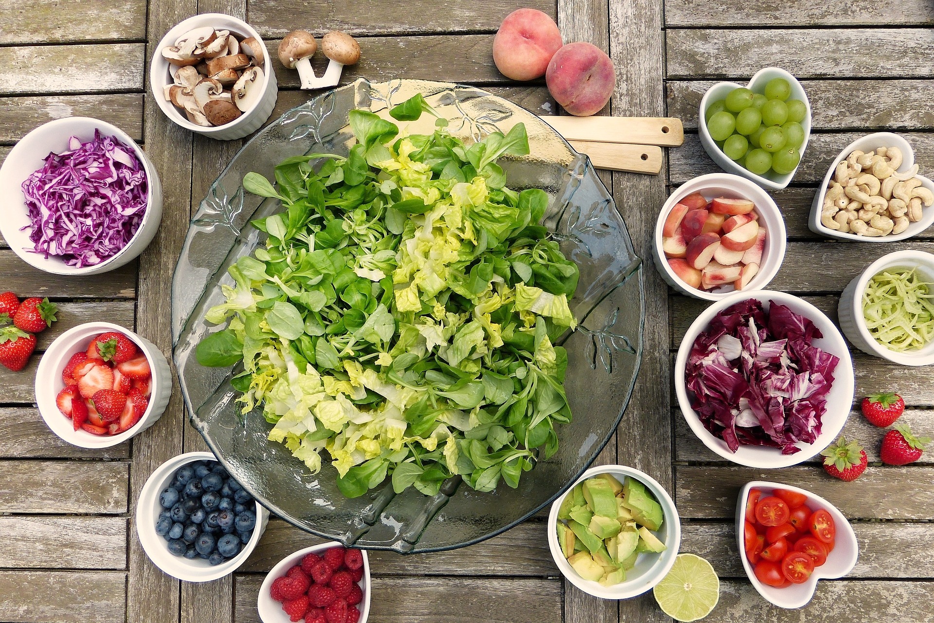 A bowl of lettuce leafs, surrounded by a variety of dishes of added extras, including cashew nuts, mushrooms, onions, strawberries, and avocado.  Our No Win No Fee Allergy Compensation solicitors discuss the severity of food allergy compensation claims, and how our solicitors can help you make a compensation claim.