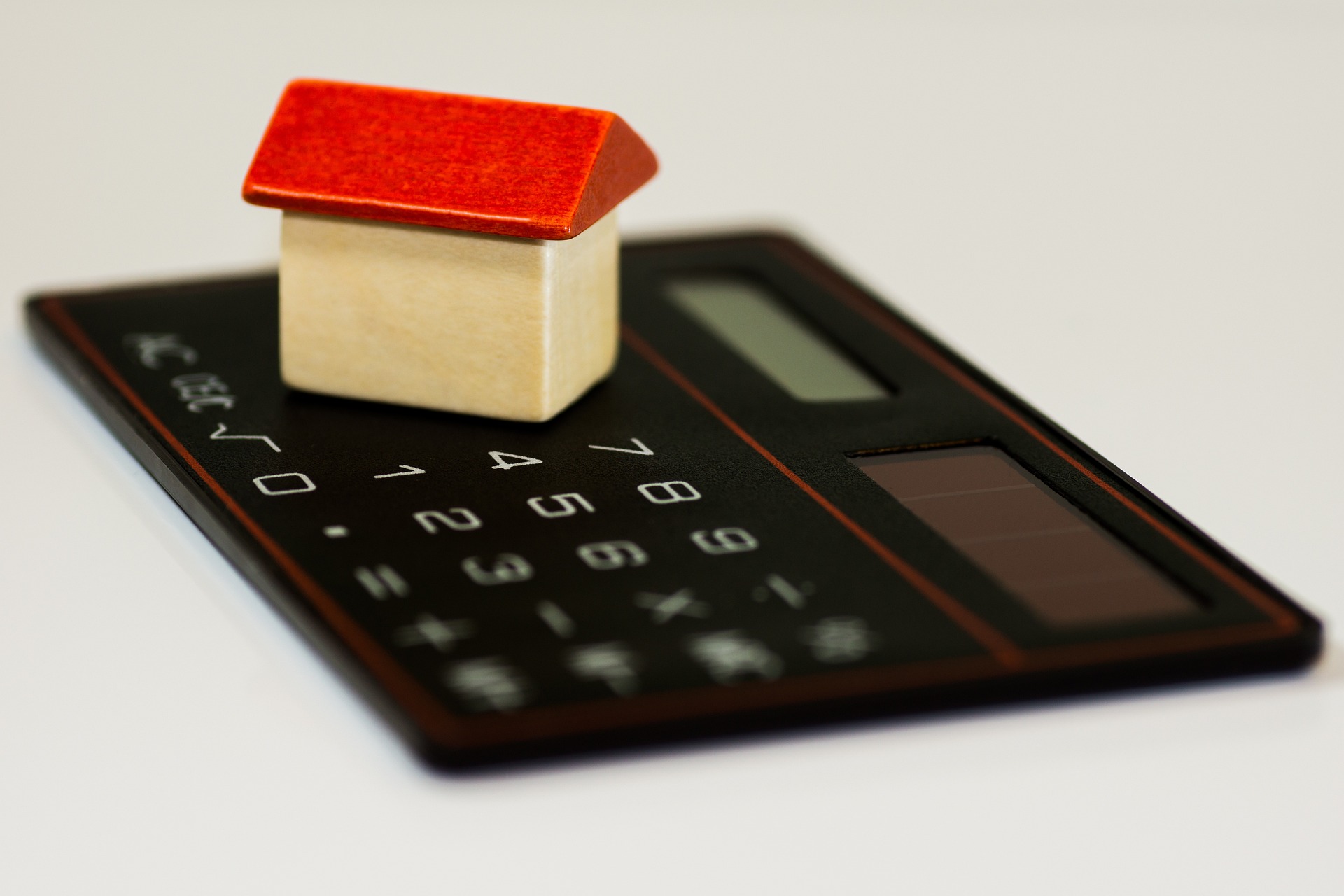 A wooden house on top of a calculator; our Conveyancing Solicitors in Lancaster discuss house buying trends in 2024.