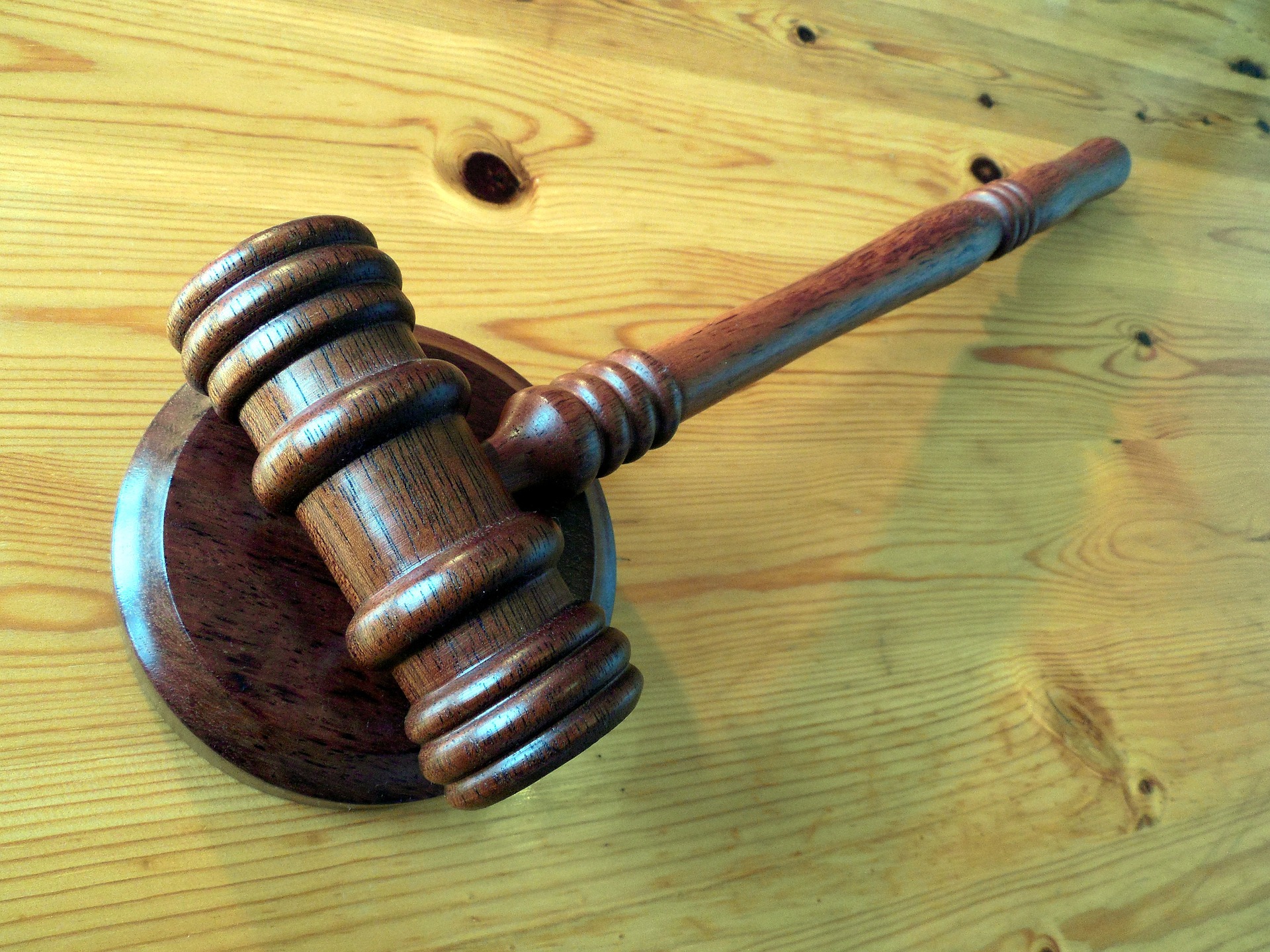 A wooden gavel on a wooden desk; our auction conveyancing solicitors can assist with the legal process of selling a house through auction, whether or online or through an auction house.