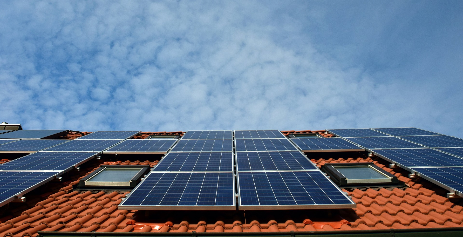 Solar Panels covering the roof of a house, with two roof windows; our Conveyancing Solicitors in Lancaster discuss whether you should buy a house with solar panels, and what it could mean for you if you do.