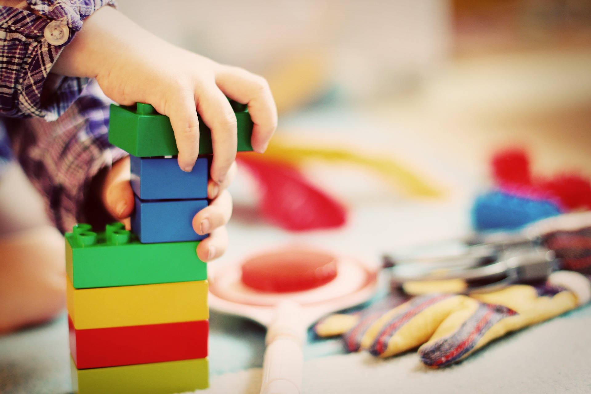 A child playing with multi-coloured building blocks, with other toys scattered around; our Wills Solicitors in Lancaster discuss appointing a guardian in your Will.  Complete your details for a call back.