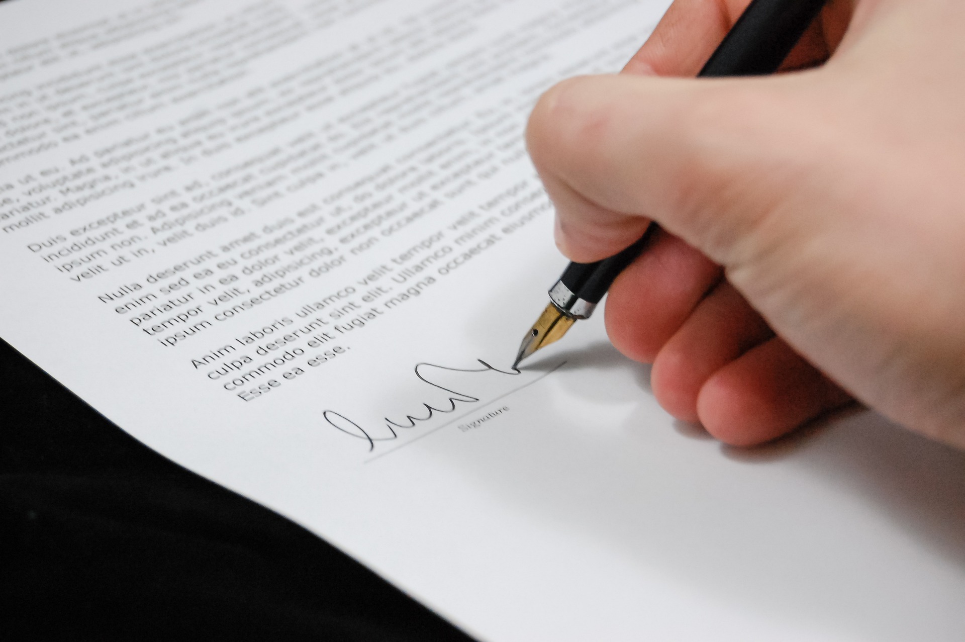 A person signing their name on a legal document, as a Settlement Agreement needs to be signed; our Settlement Agreement Employment Solicitors discuss the documents and why you need a solicitor for a settlement agreement.