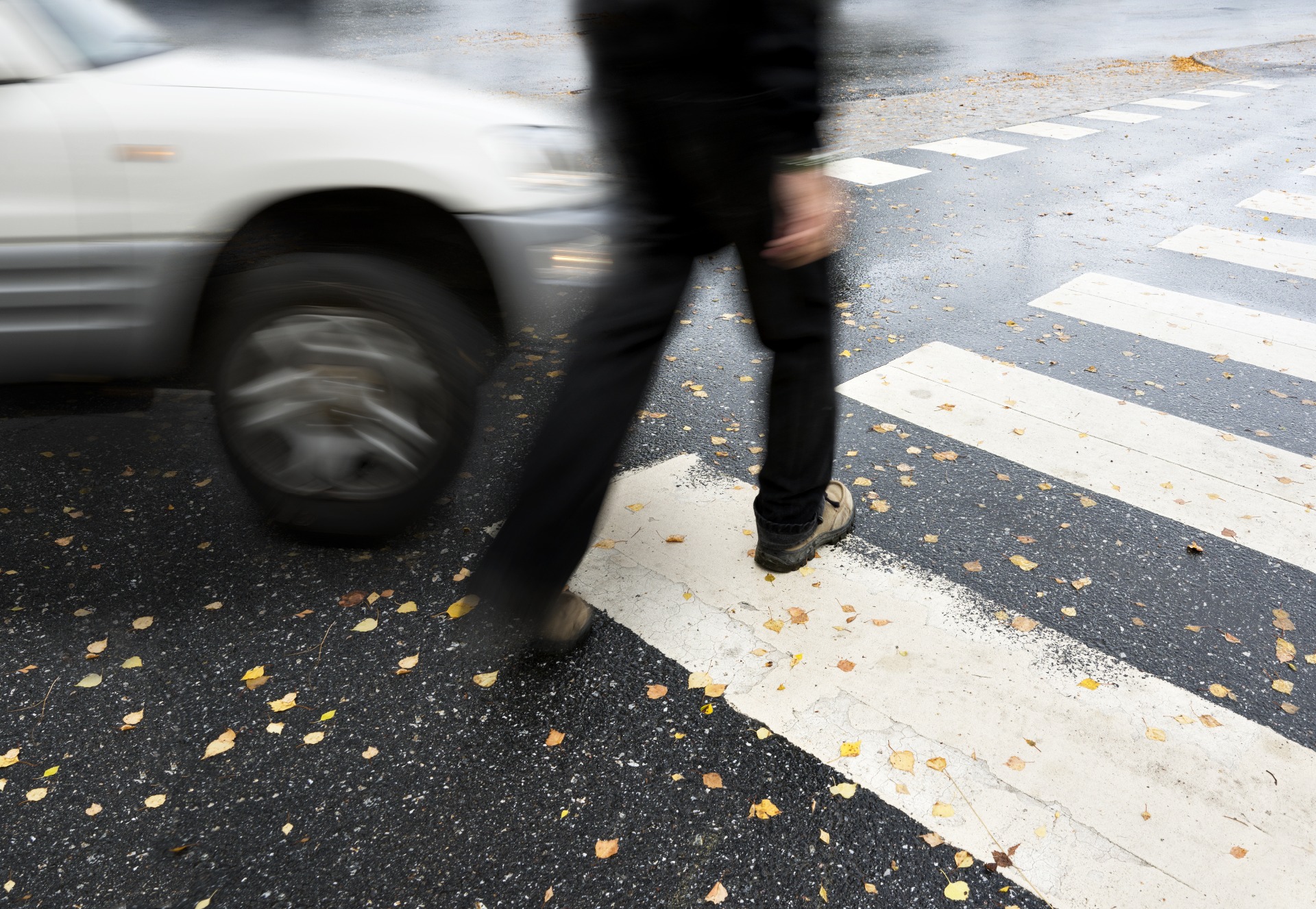A person crossing a zebra crossing, being hit by a car.