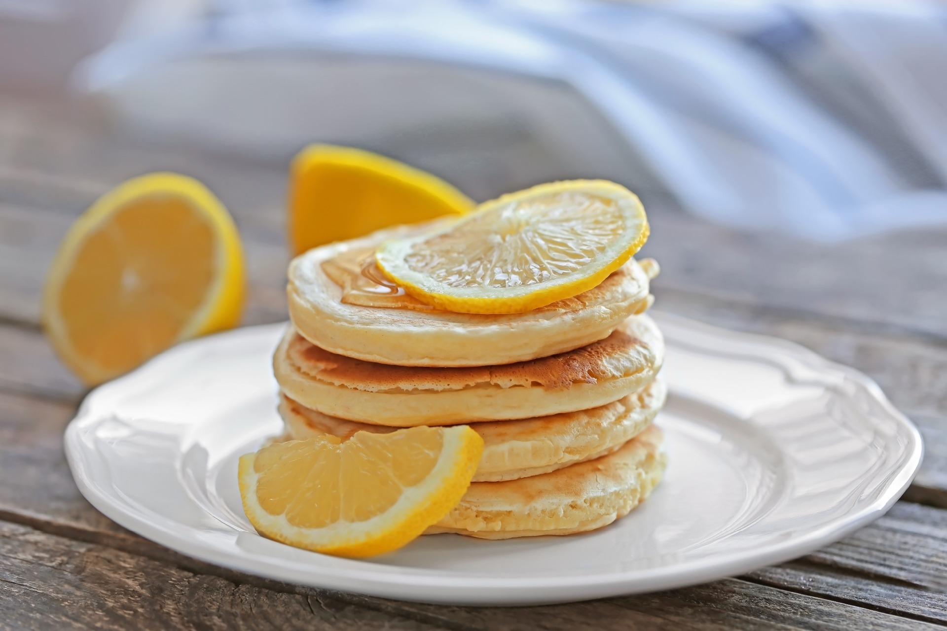 A stack of small, evenly sized pancakes with lemon slices on top.
