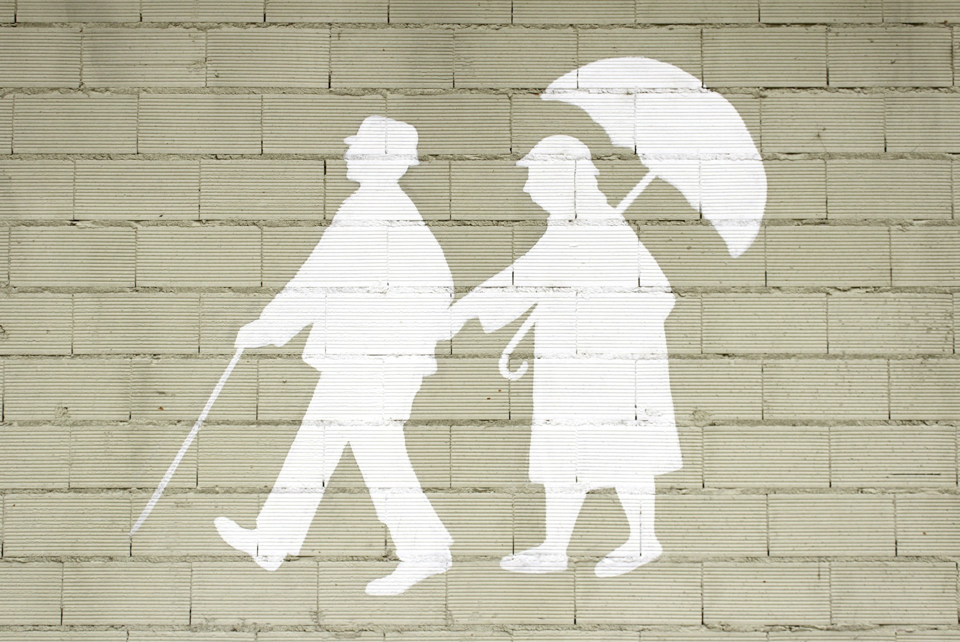 An outline of a couple, one holding an umbrella, and the other holding a walking stick, painted onto a Wall; our Wills Solicitors in Lancaster discuss mirror Wills, how much they cost, and how our team can help to prepare them.