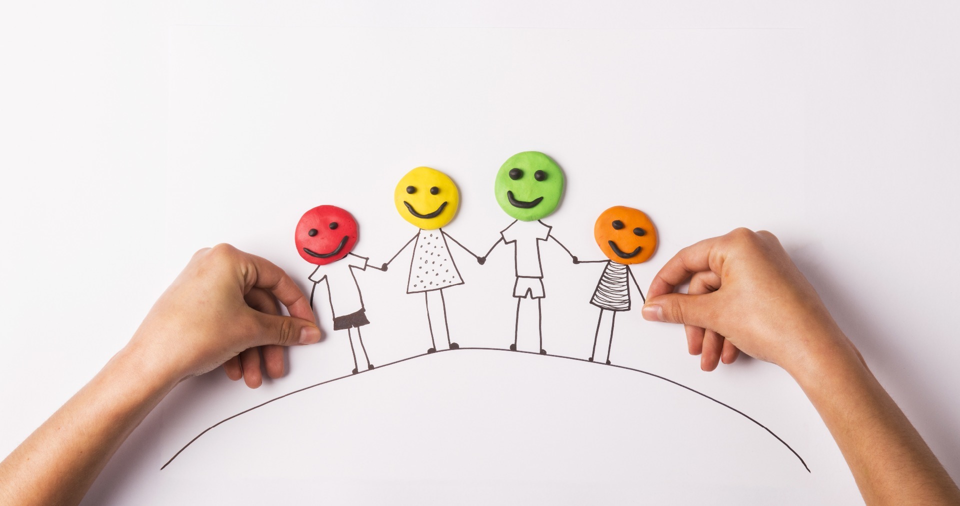 A family drawn in black pen, with play-doh faces in different colours, holding hands.