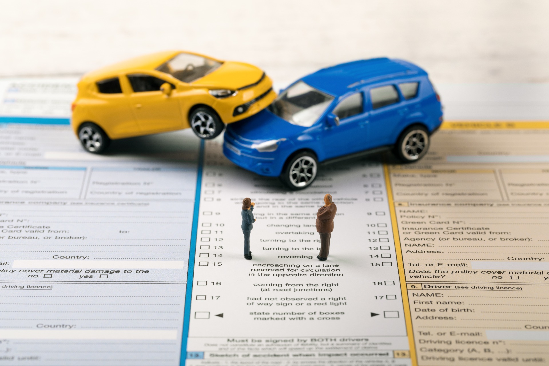 A toy yellow and blue car on top of an insurance form.