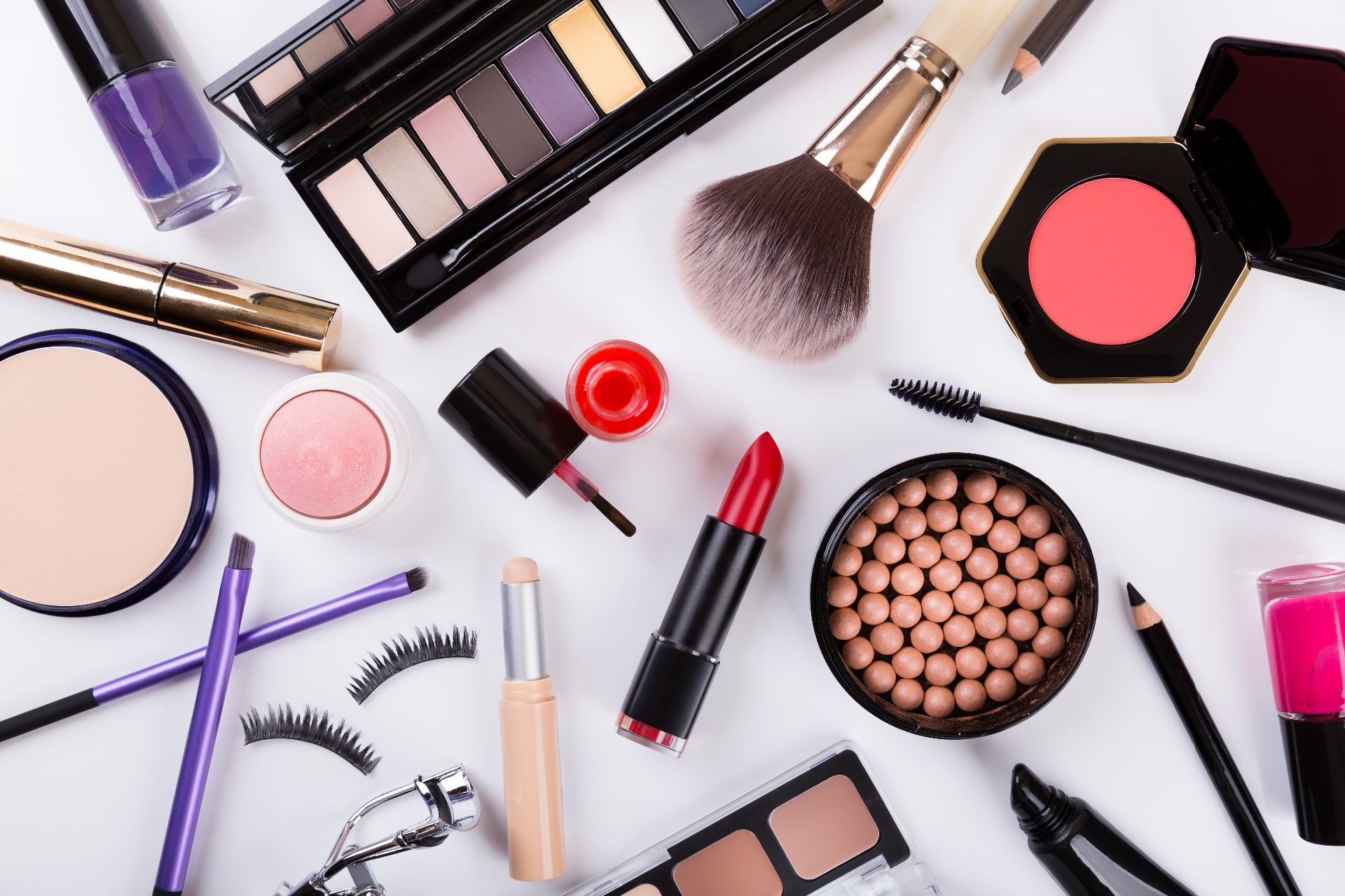 An array of beauty products, such as mascara, eyeliner, eyeshadow, blush, foundation and eyelashes.
