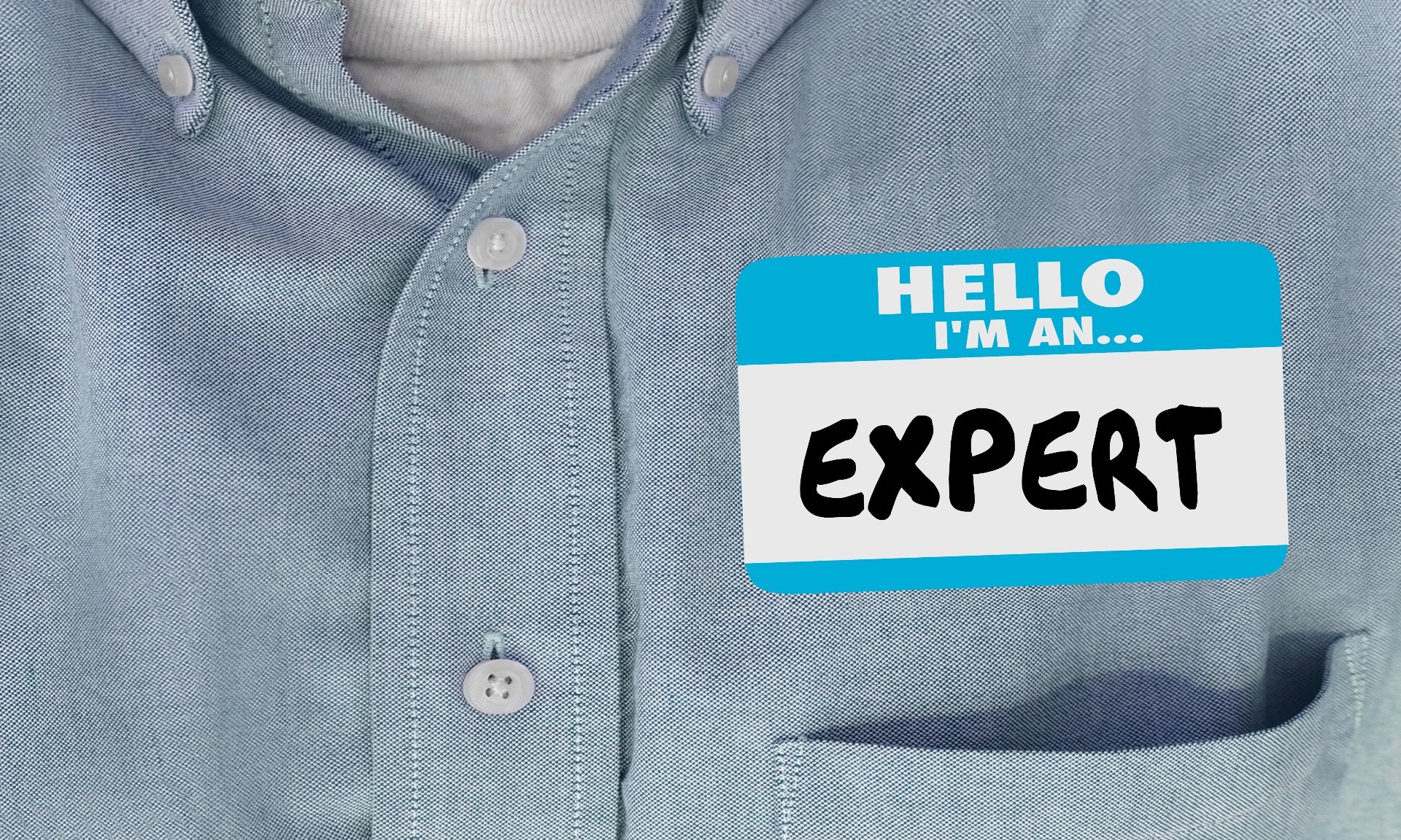A person wearing a blue shirt, with a name tag on which says "Hello, I'm an EXPERT".  Our No Win No Fee Solicitors discuss medical experts in cycling injury claims.