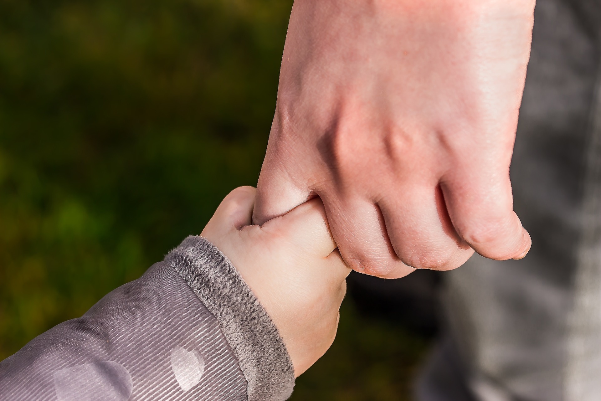 A child holding an adult's hand.