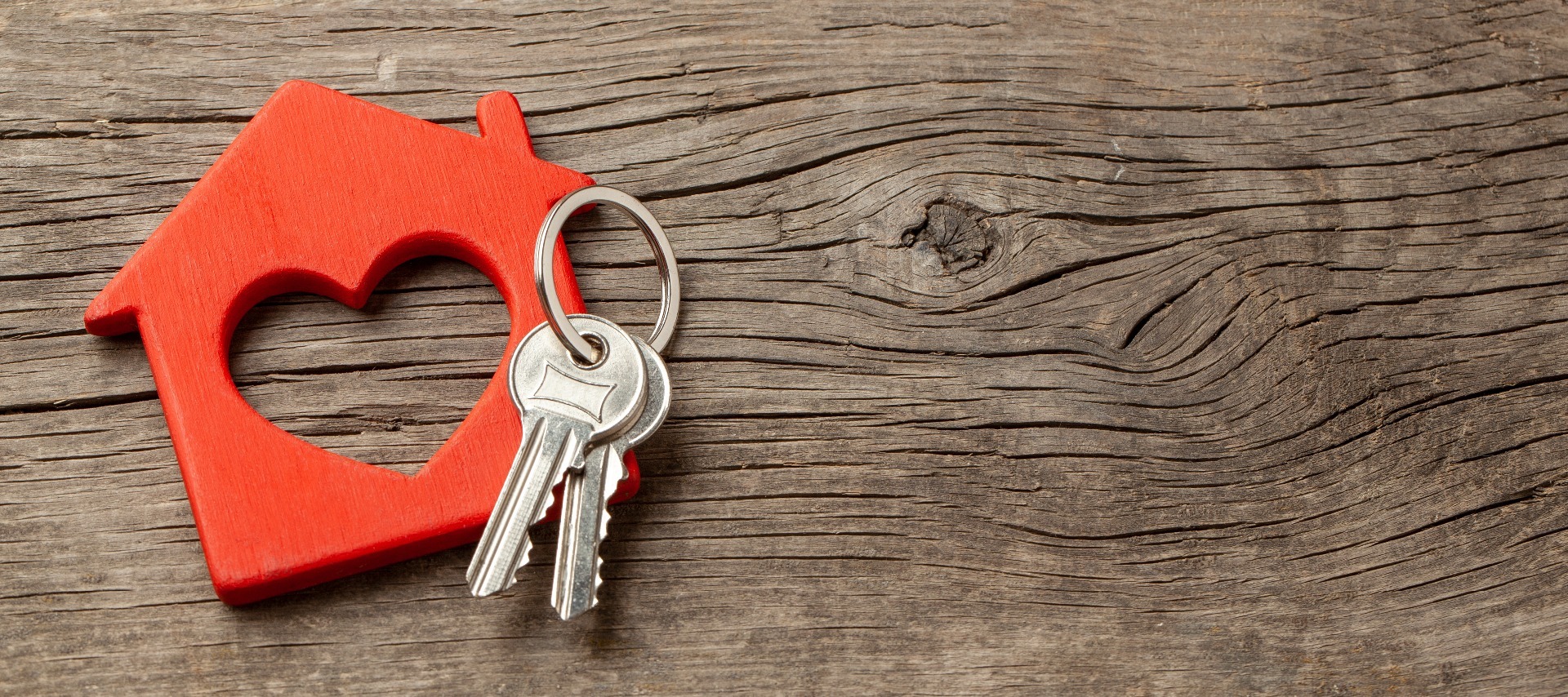A set of house keys on a red, wooden house shape, with a heart cut out of the centre; our Conveyancing Solicitors in Garstang are here to assist with your house sale or purchase.