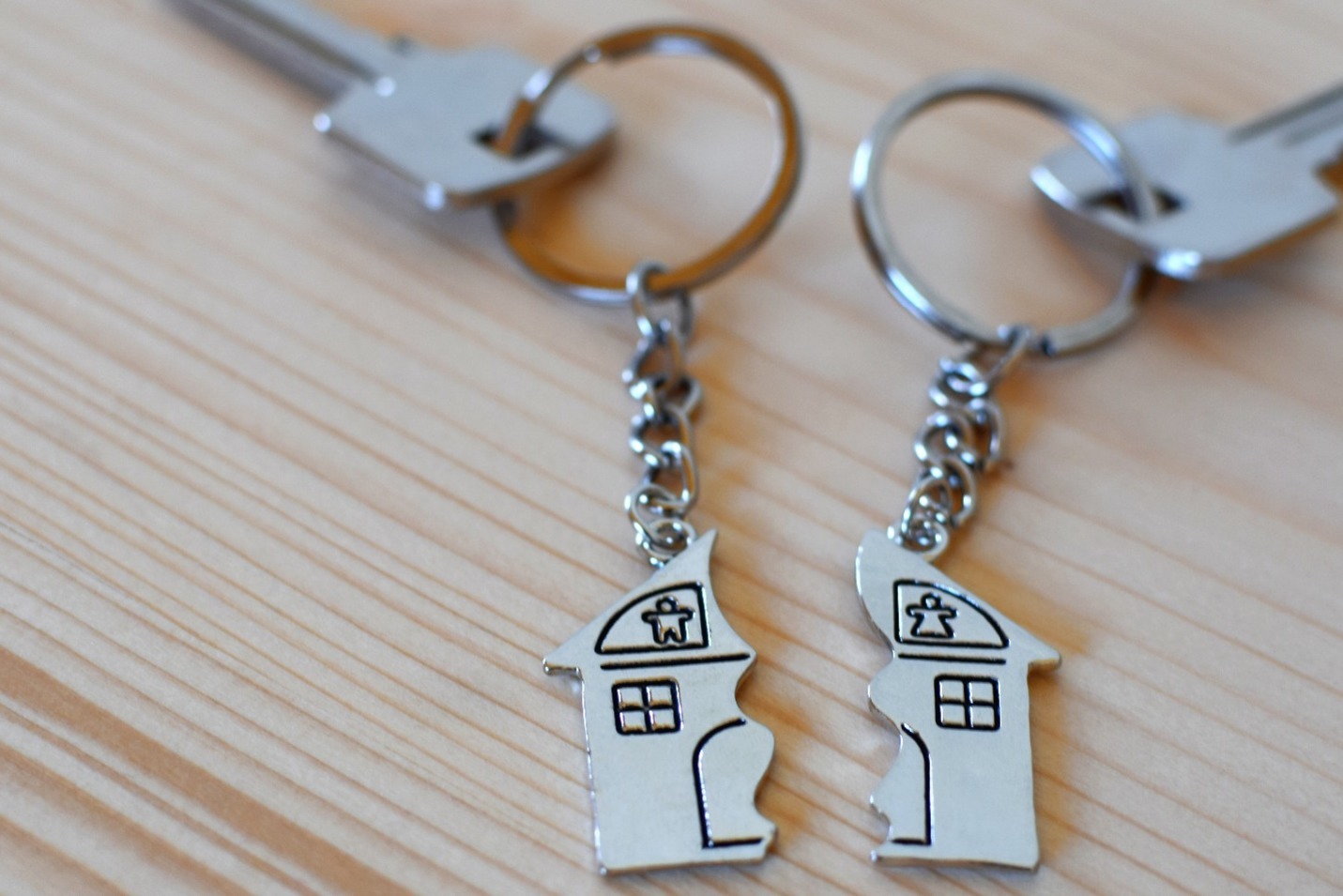 Two keys, each attached to their own keyring showing half of a house.