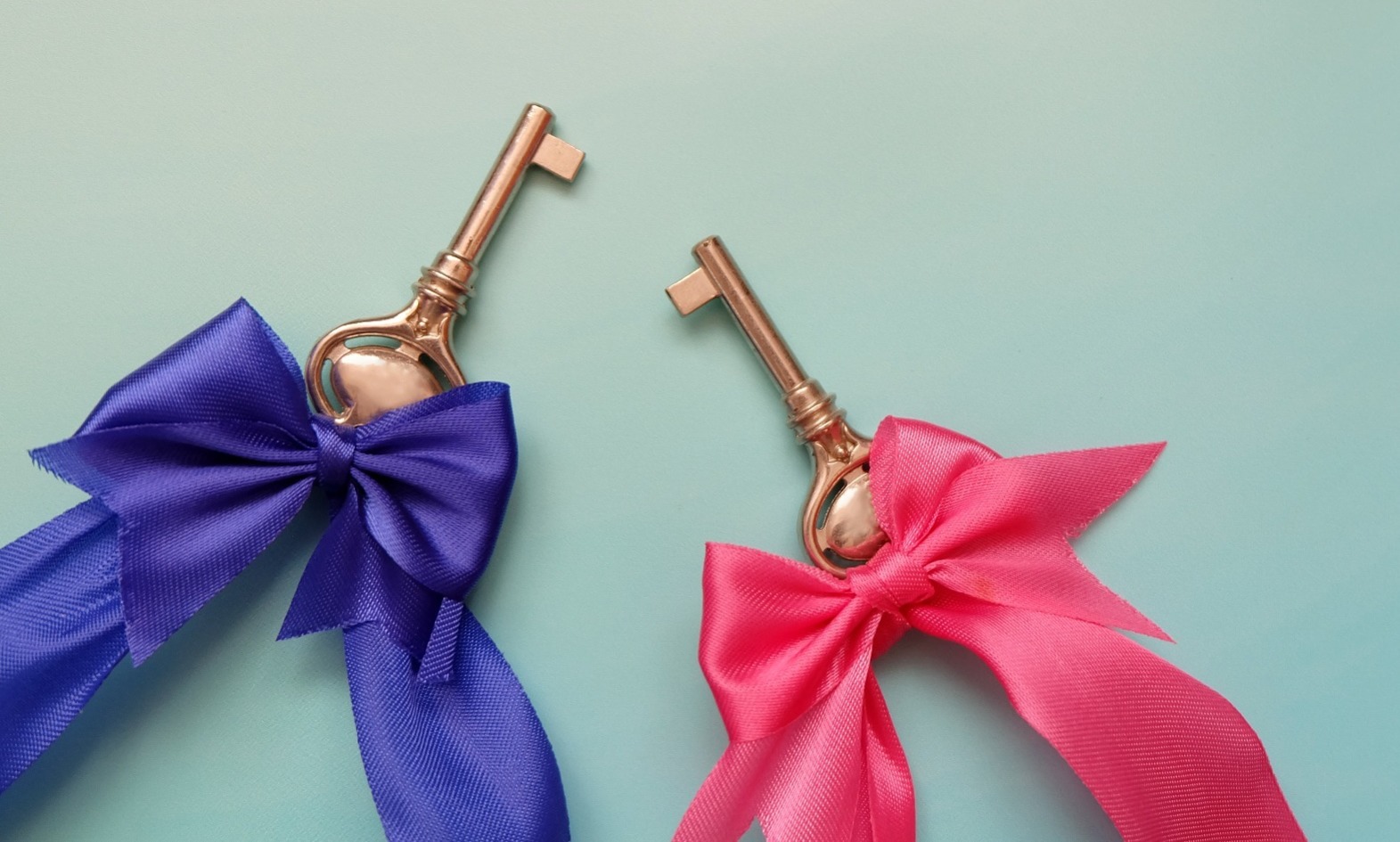 Two keys, one with a purple ribbon and the other with a pink ribbon; our Conveyancing Solicitors are property equity transfer solicitors.