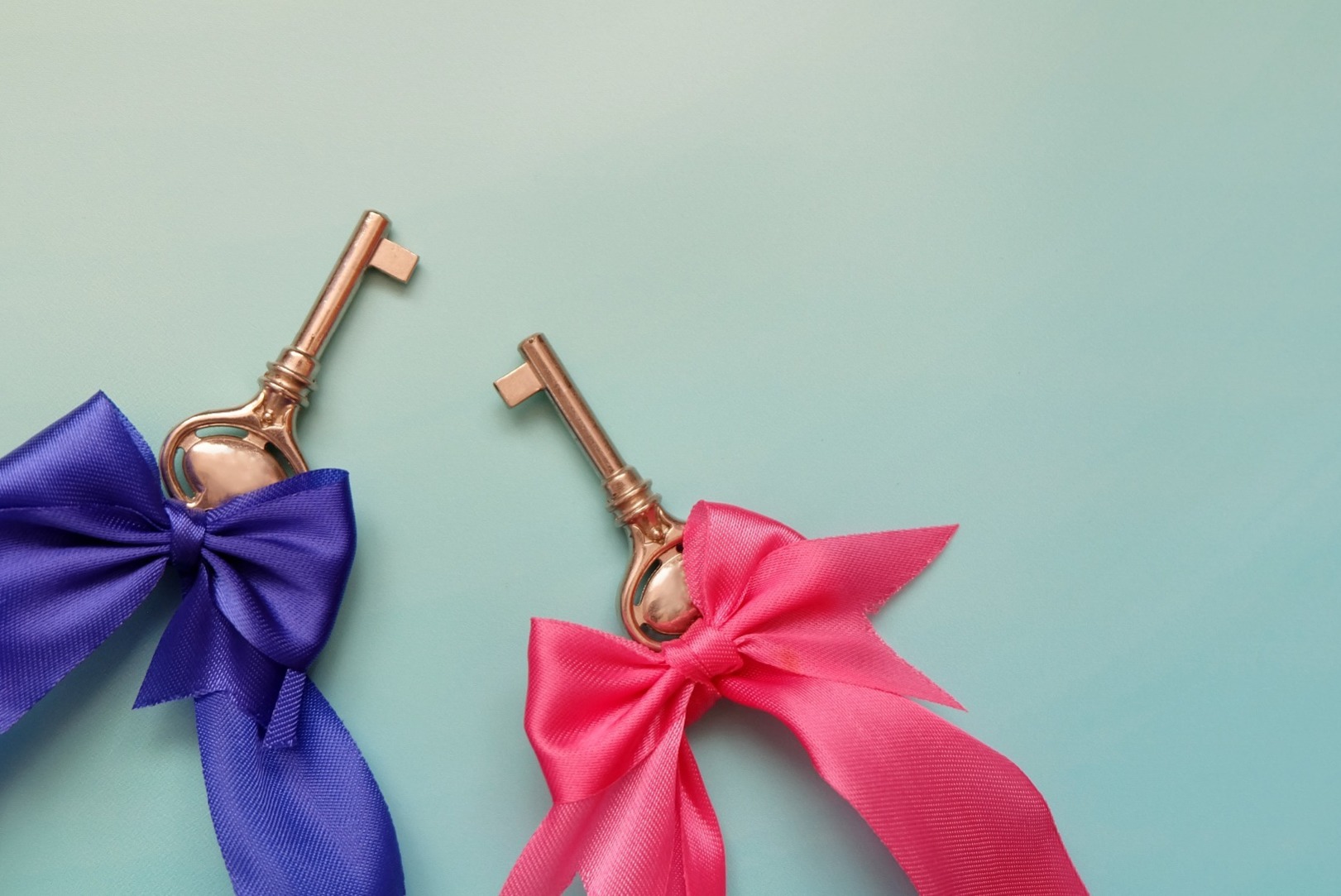 Two keys, tied with different coloured ribbons.