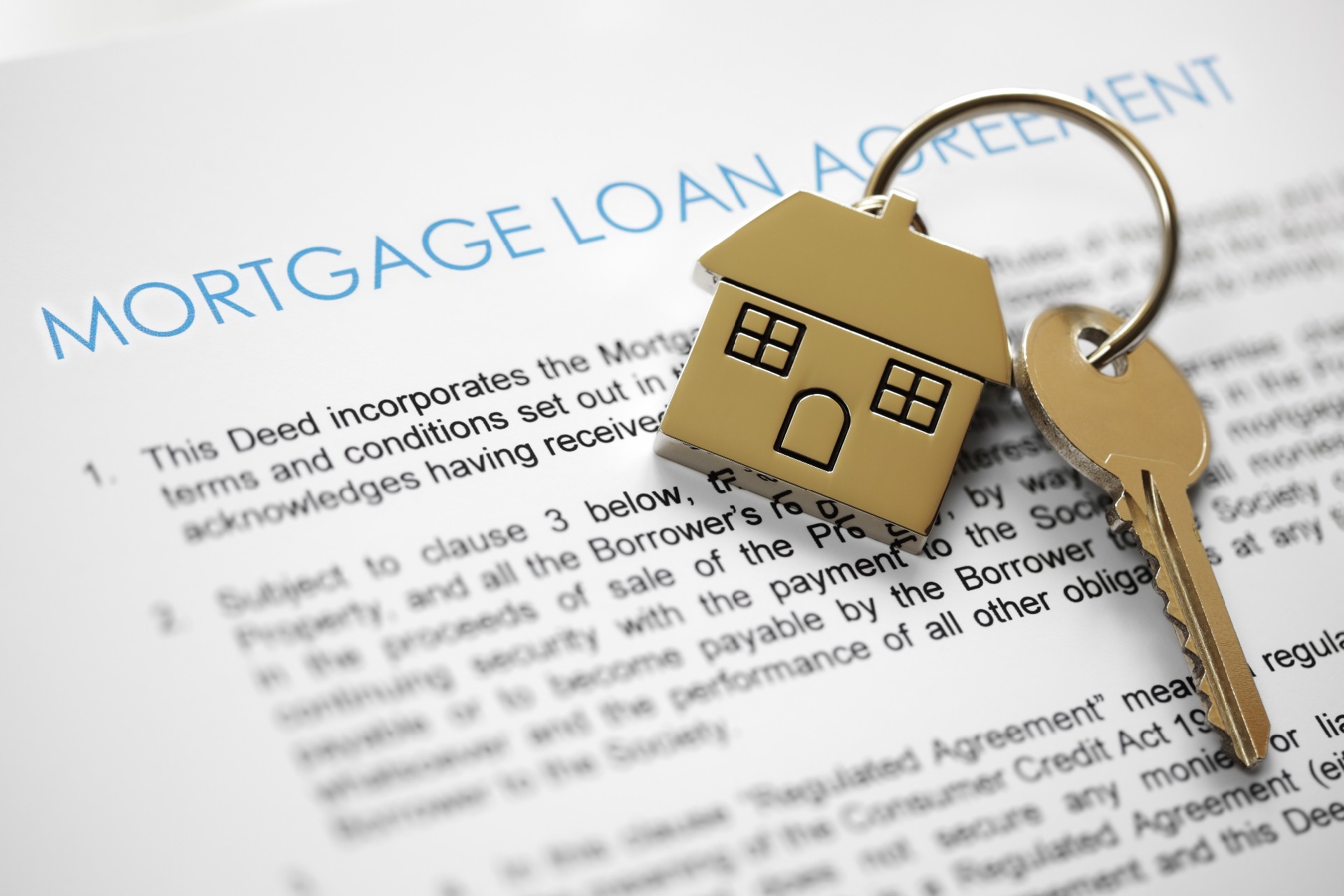 A house keyring with a door key, on top of a mortgage deed; our Conveyancing Solicitors in Preston discuss one per cent mortgages