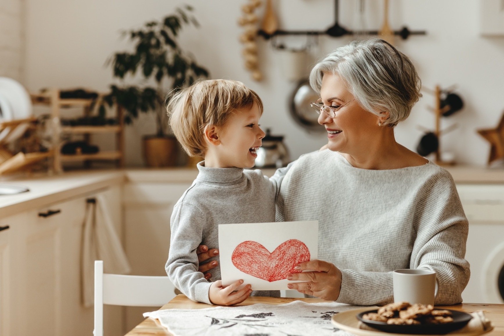 An adult holding a child, sat in a kitchen, with the child's artwork in their hands; our Wills Solicitors discuss what happens when someone dies without a Will.  Visit this page, by clicking the image.